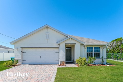 a white house with a garage door and a lawn