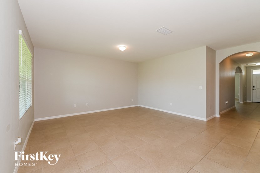 a empty living room with tiled flooring and a hallway