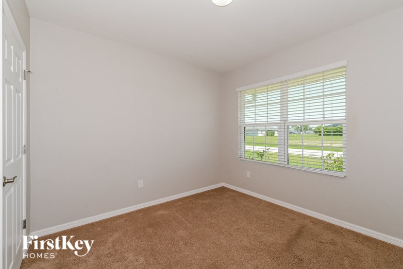 a bedroom with a large window and a carpet