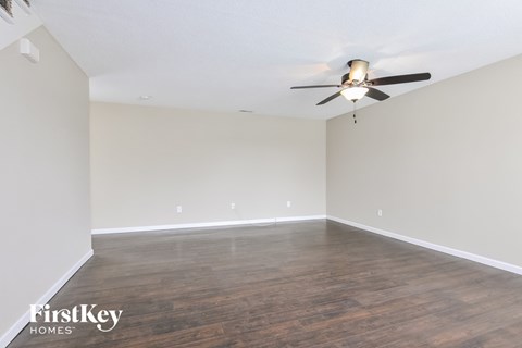 A room with a ceiling fan and wooden flooring.