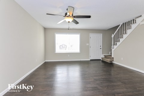 A spacious room with a staircase and a ceiling fan.