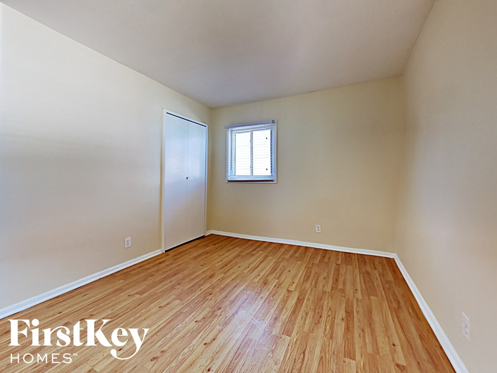 an empty room with wood flooring and a window