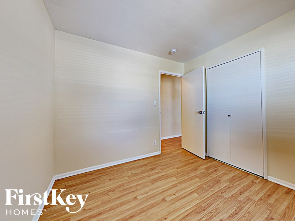 a bedroom with wood flooring and white closets