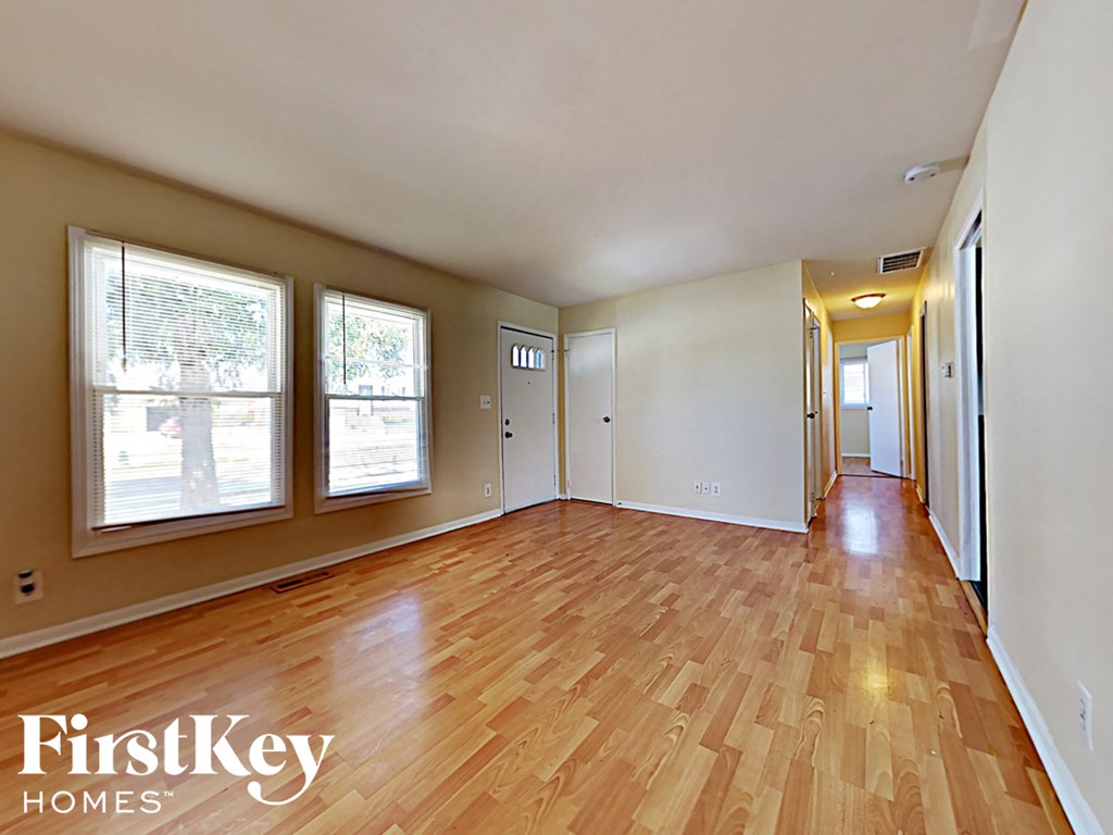 an empty living room with wood flooring and windows