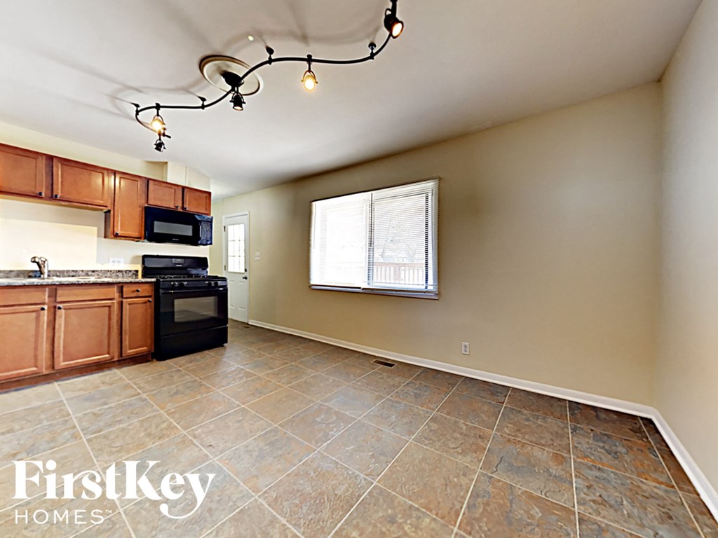 a kitchen with wood cabinets and black appliances and tile flooring