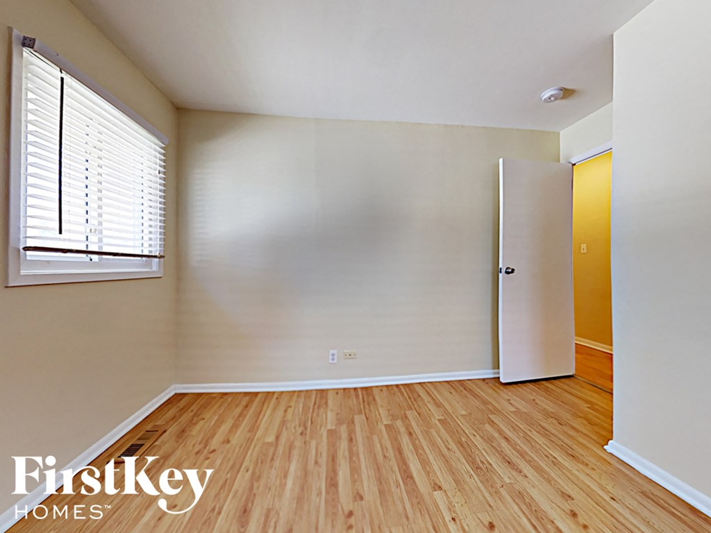 an empty bedroom with wood flooring and a white door