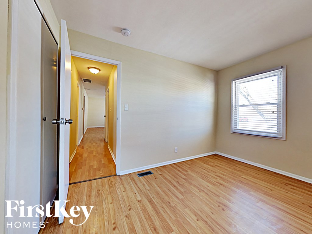 an empty living room with wood floors and a window