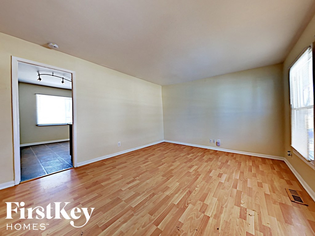 an empty living room with wood flooring and a door to a closet