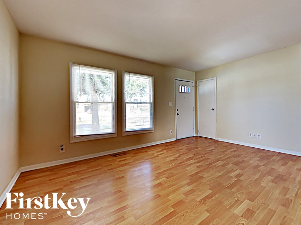 an empty living room with wood flooring and three windows