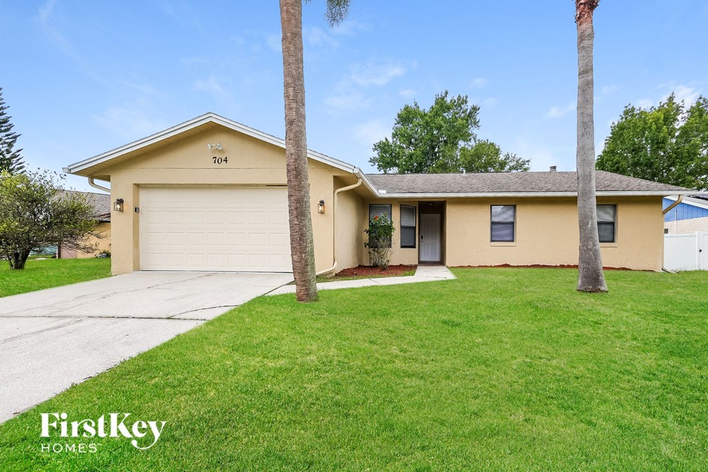 a beige house with a lawn and palm trees