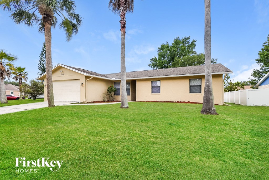 a yellow house with palm trees in a yard