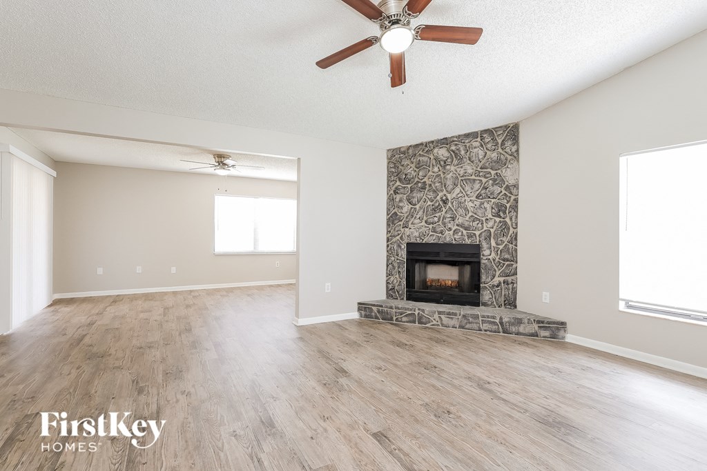an empty living room with a fireplace and a ceiling fan