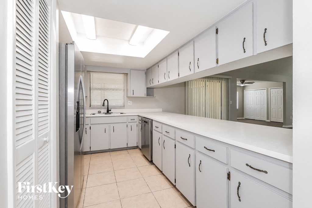 a white kitchen with white cabinets and a stainless steel refrigerator