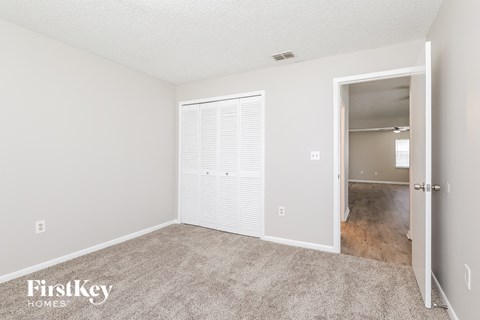a spacious living room with carpet and a door to a closet