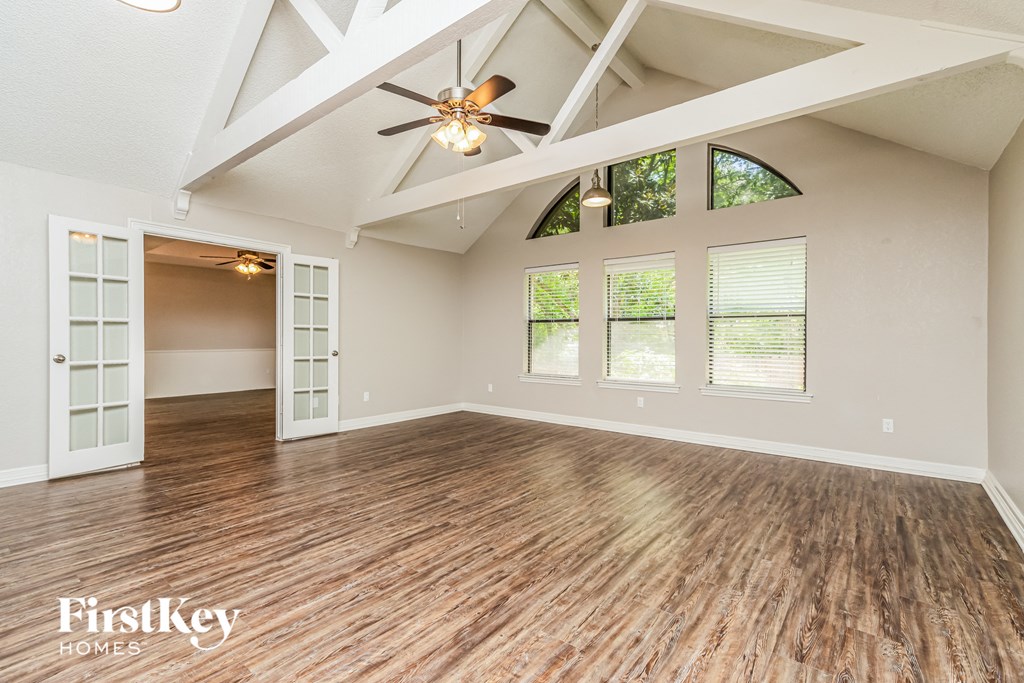 an empty living room with a ceiling fan and windows