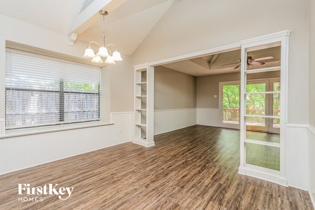 the living room and dining room of a house with wood flooring and a window
