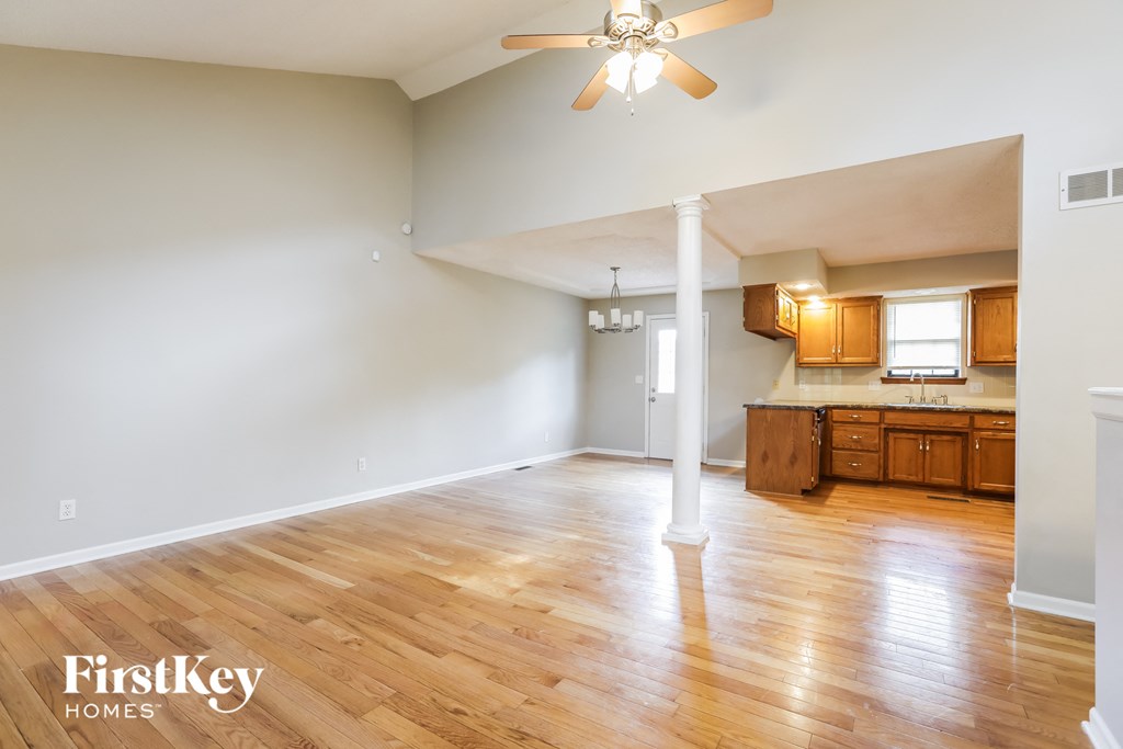 A spacious room with wooden floors and a ceiling fan.