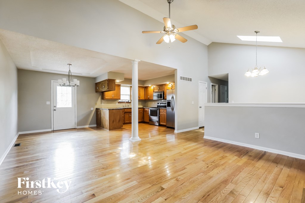 A spacious living room with wooden floors and a ceiling fan.