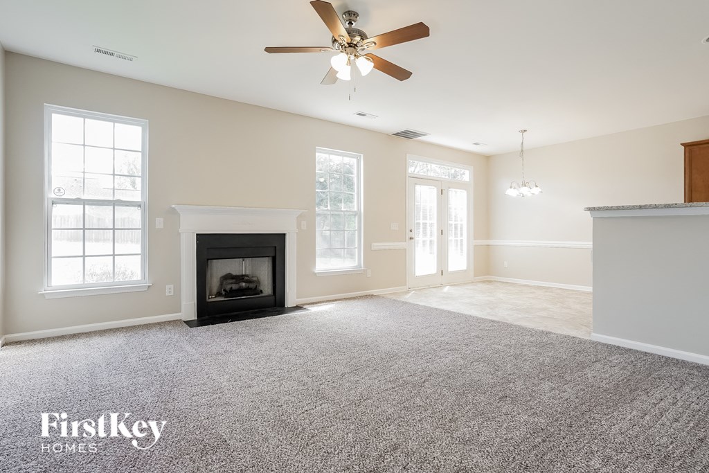 A spacious room with a fireplace and a ceiling fan.