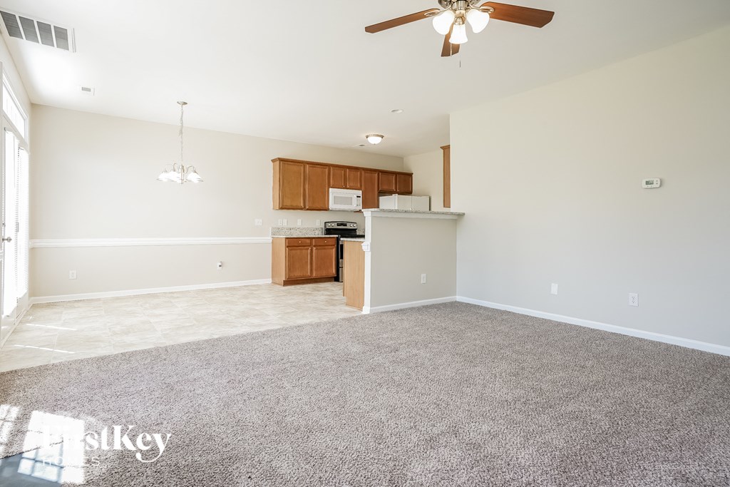 A spacious living room with a kitchenette in the background.
