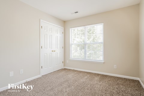 A room with a carpeted floor, a door, and a window.