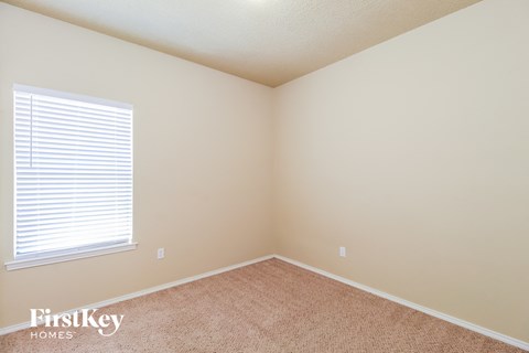 a bedroom with beige carpet and a window