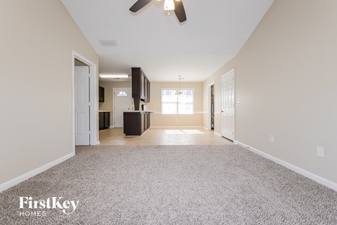 A spacious room with a carpeted floor and a ceiling fan.