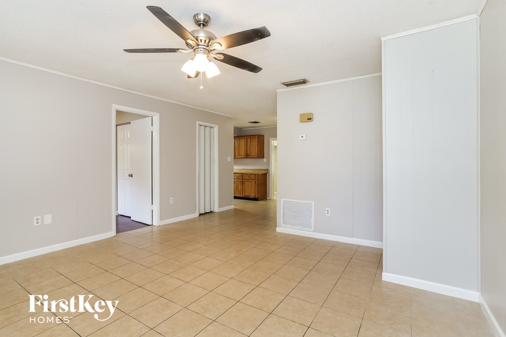 A spacious room with a ceiling fan and beige tiled flooring.