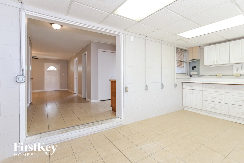 A kitchen area with a white tile floor and white walls.