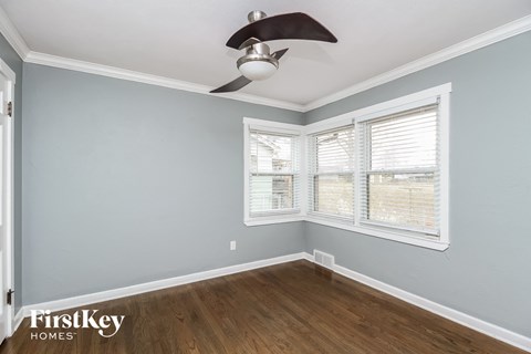 a bedroom with two windows and a ceiling fan