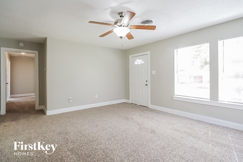 A spacious room with a ceiling fan and two doors.
