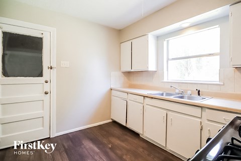 A kitchen with white cabinets and a black stove top oven.