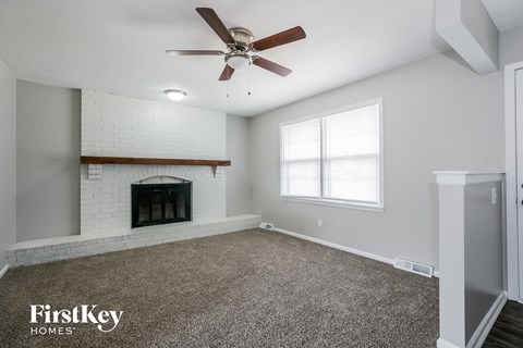 A spacious room with a fireplace and a ceiling fan.