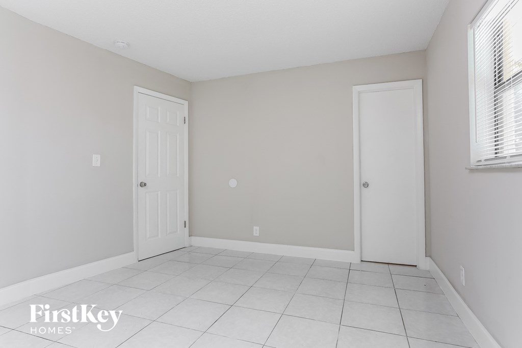 a empty room with a white tile floor and a white door
