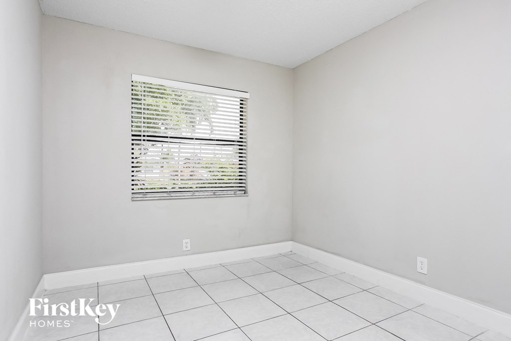 a white room with a window and a white tiled floor