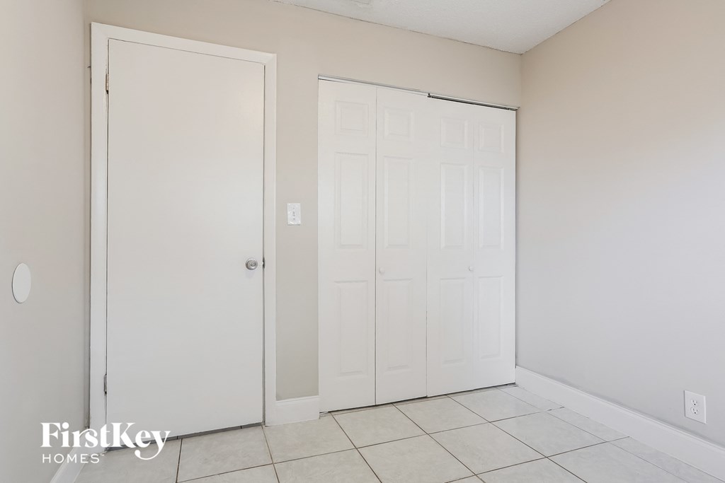a room with two closets and a tiled floor and a white door
