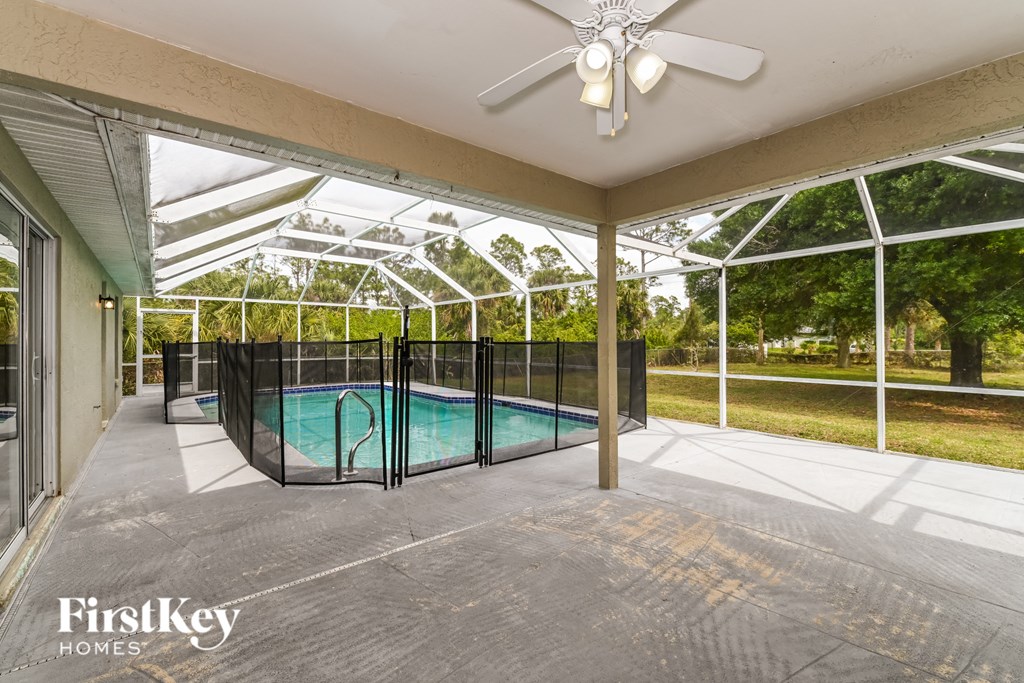 a patio with a pool and a ceiling fan and glass doors