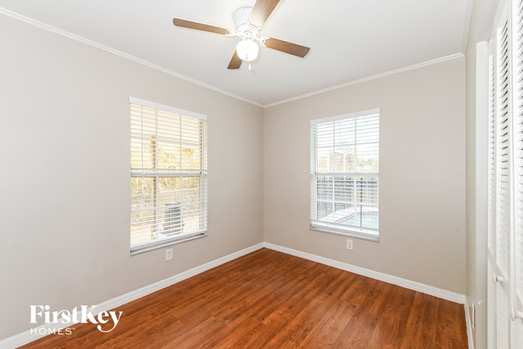a bedroom with wood floors and a ceiling fan