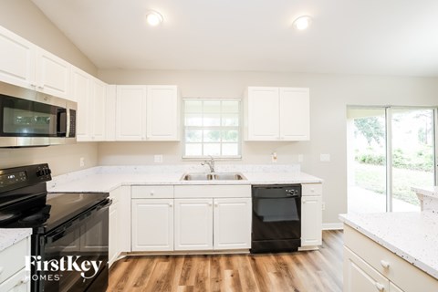 A kitchen with white cabinets and a black stove top oven.