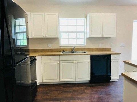A kitchen with white cabinets and a black refrigerator.