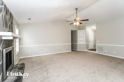 an empty living room with a fireplace and a ceiling fan