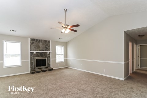 an empty living room with a ceiling fan and a fireplace