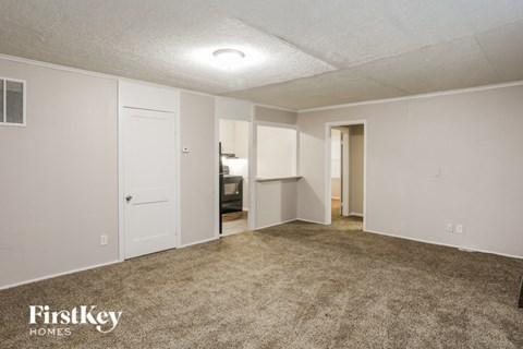 an empty living room with carpet and white walls