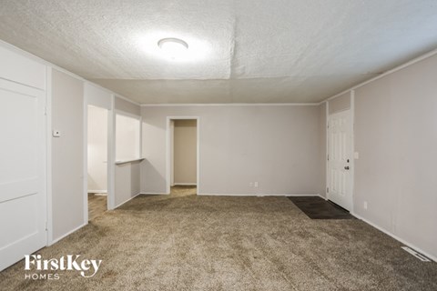 an empty living room with carpet and white walls