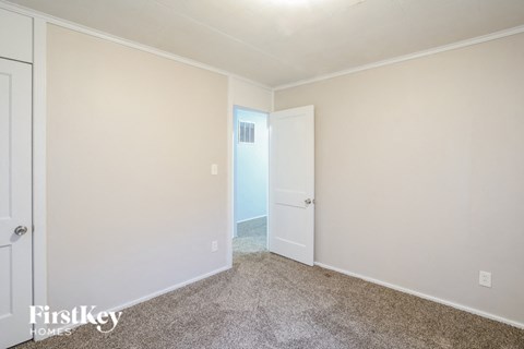 a bedroom with white walls and carpet and a door to a closet
