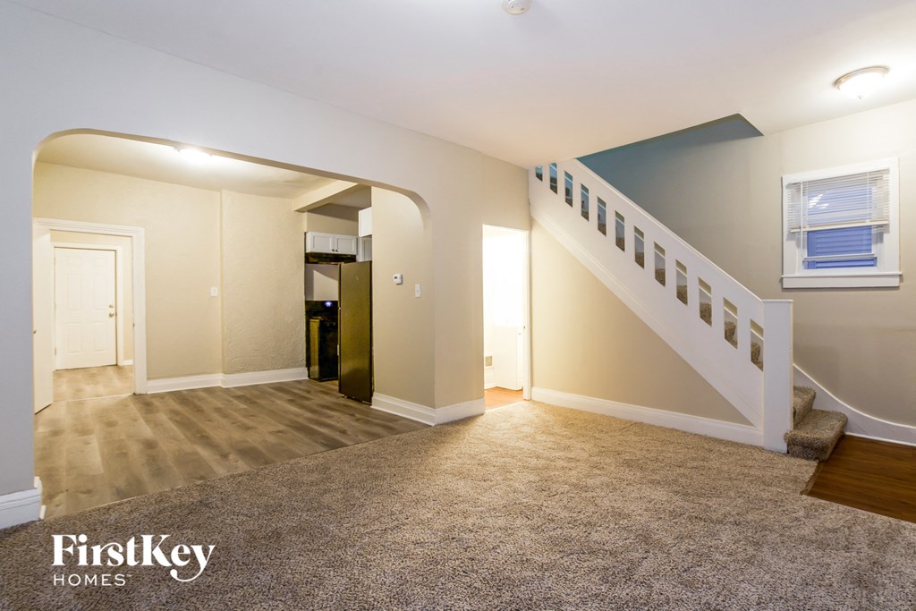 a living room with a staircase and a carpeted floor