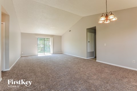 a spacious living room with carpet and a door to the kitchen