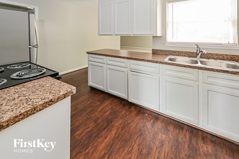 A kitchen with a stove top oven and white cabinets.