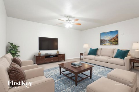 A living room with a brown couch, a coffee table, and a painting on the wall.
