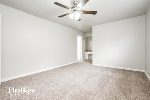 a spacious living room with carpet and a ceiling fan
